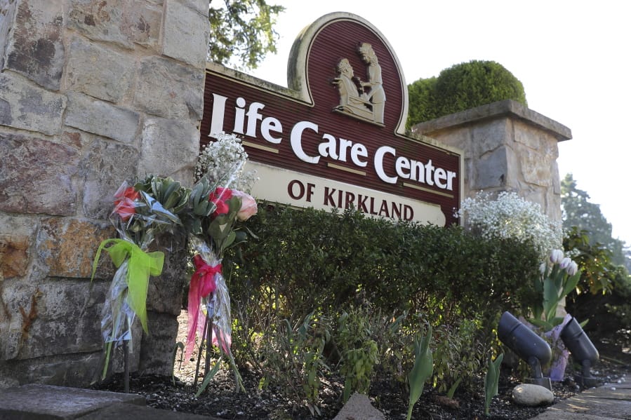 Flowers left next to the sign that marks the entrance to the parking lot of the Life Care Center in Kirkland, Wash. are shown Monday, March 9, 2020, near Seattle. The nursing home is at the center of the outbreak of the COVID-19 coronavirus in Washington state. (AP Photo/Ted S.
