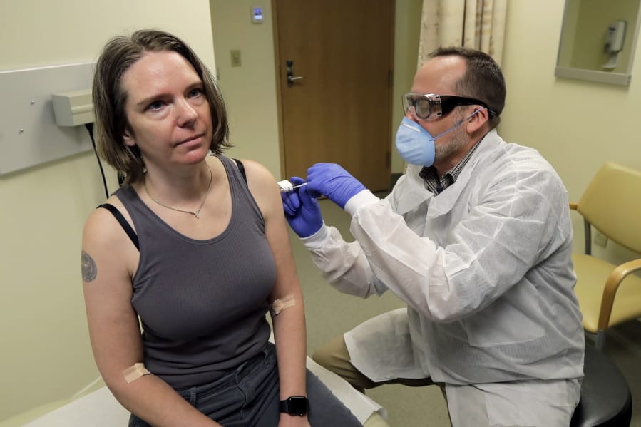 A pharmacist gives Jennifer Haller, left, the first shot in the first-stage safety study clinical trial of a potential vaccine for COVID-19, the disease caused by the new coronavirus, Monday, March 16, 2020, at the Kaiser Permanente Washington Health Research Institute in Seattle. (AP Photo/Ted S.