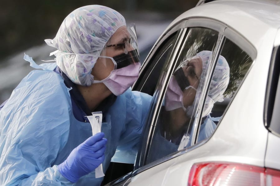 Laurie Kuypers, a registered nurse, reaches into a car to take a nasopharyngeal swab from a patient at a drive-through COVID-19 coronavirus testing station for University of Washington Medicine patients Tuesday, March 17, 2020, in Seattle. The appointment-only drive-through clinic began a day earlier. Health authorities in Washington reported more COVID19 deaths in the state that has been hardest hit by the outbreak.