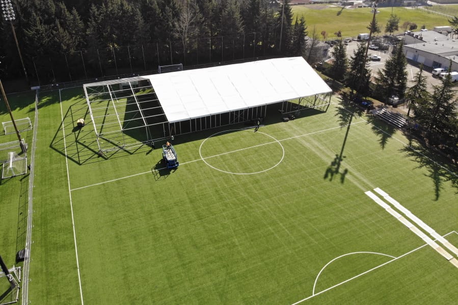 In this aerial drone photo, workers erect a temporary field hospital for use by people unable to isolate and recover from COVID-19 in their own homes on a soccer field Thursday, March 19, 2020, in the Seattle suburb of Shoreline, Wash.
