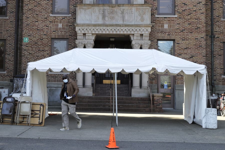 An employee wears a mask as he walks near an entrance to Western State Hospital, Thursday, March 19, 2020, in Lakewood, Wash. A patient and a worker at the facility, Washington state&#039;s largest psychiatric hospital, have tested positive for COVID-19. The tent shown behind him will eventually be used for screening employees for symptoms of the virus as they arrive for work. (AP Photo/Ted S.