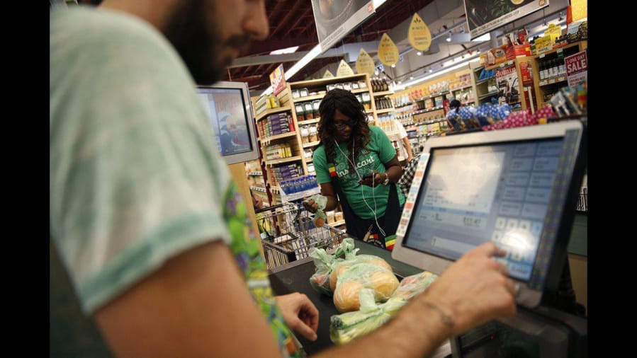 Whole Foods cashier Jason Ellsworth rings up groceries purchased by Instacart shopper Kara Pete. Instacart shoppers and delivery workers went on strike Monday over lack of protection against the coronavirus.