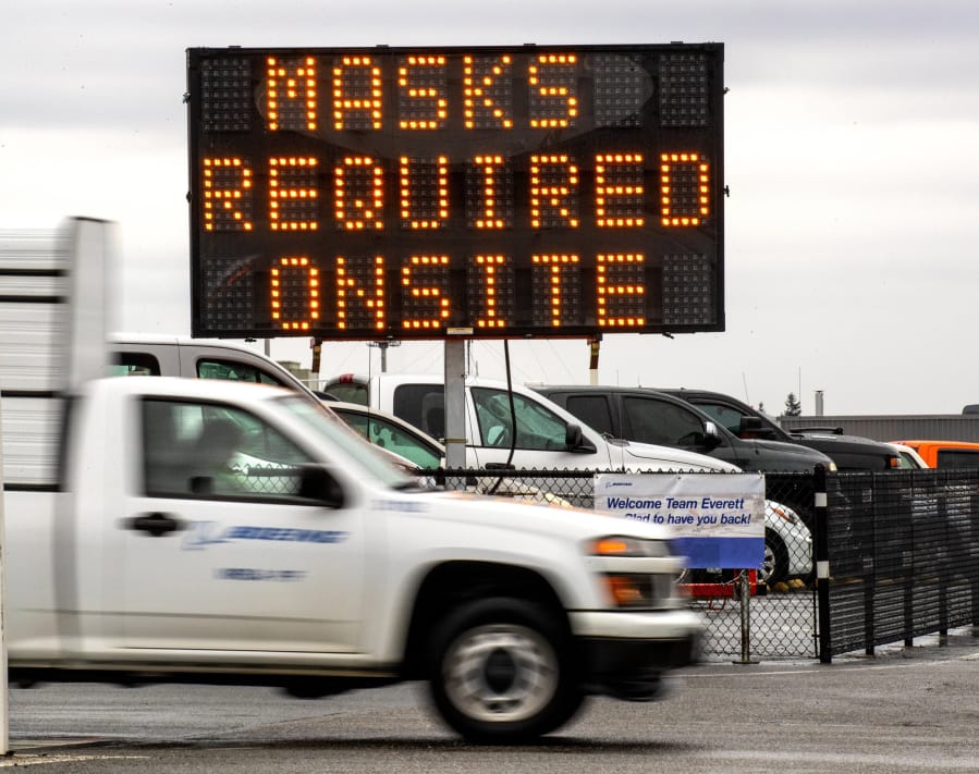 A sign advising that masks are required stands near an entry gate at the Boeing final assembly plant in Everett, Wash. on Wednesday, April 22, 2020. Boeing is restarting production of airplanes in the Seattle area, sending about 27,000 employees back to work after all airplane production was halted because of the coronavirus.