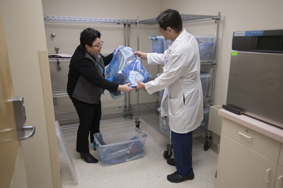 Michelle Bart of the National Women&#039;s Coalition Against Violence &amp; Exploitation, left, talks with Victor Garcia, director of Service Lines, as they look over a donation of clothes for survivors of domestic violence at PeaceHealth Southwest Medical Center&#039;s emergency room.