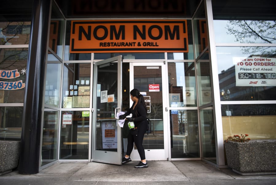 Nom Nom operations manager Sol Contreras wipes down the door handles as she opens up the restaurant at 801 C St. Nom Nom is still open for takeout and delivery orders.