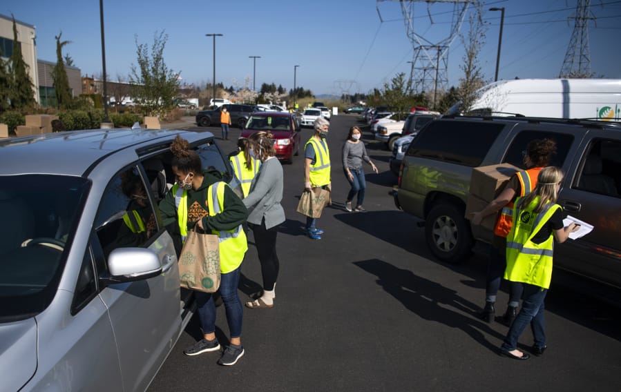 Cars fill the parking lots and line the streets surrounding the Clark County Food Bank to pick up food Tuesday afternoon. The food bank packed boxes and bags filled with food to give away to people in need during the COVID-19 pandemic.