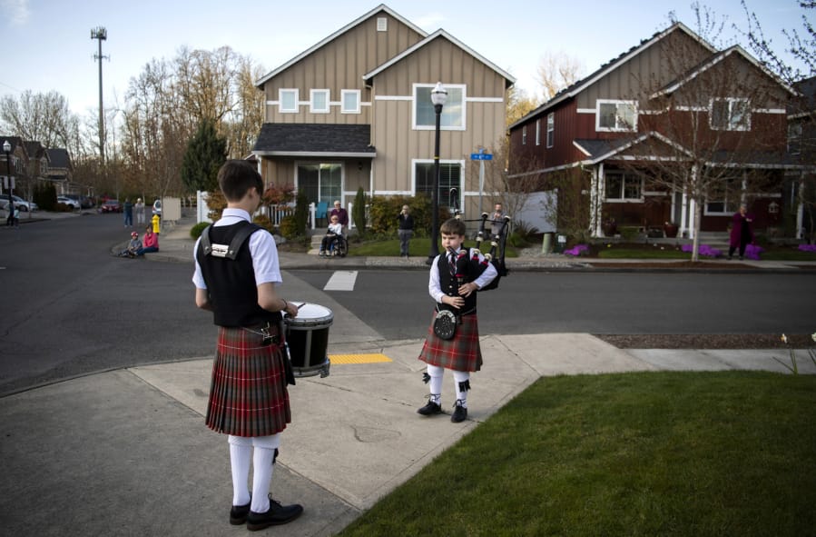 Drummer Daniel Gillespie, 15, and bagpiper Logan Gillespie, 12, perform a brief concert Wednesday for their Battle Ground neighbors. At far right across the street is Bev Lohrman, a night-shift nurse who cares for COVID-19 patients in the intensive care unit at PeaceHealth Southwest Medical Center. Every time the brothers play her late mother&#039;s favorite song, &quot;Amazing Grace,&quot; Lohrman said she hears her mother reassuring her that everything will be OK.