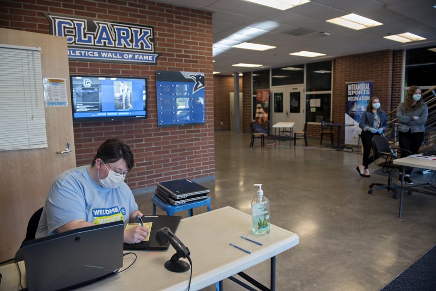 Library staff member Amanda Brown, left, prepares laptops in O&#039;Connell Sports Center for student pickup at Clark College on Monday morning. The college moved almost all its classes online due to shutdown orders connected to the novel coronavirus.