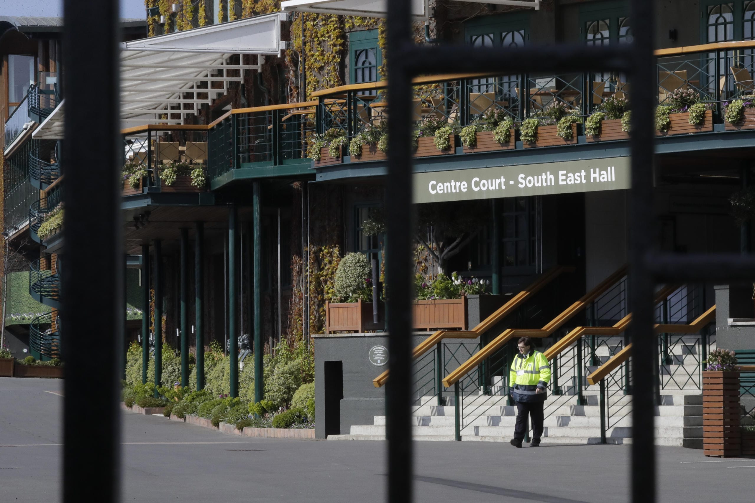 A security guard inside the main gates to Wimbledon as it is announced the the Wimbledon tennis Championships for 2020 has been cancelled due to the coronavirus in London, Wednesday, April 1, 2020.