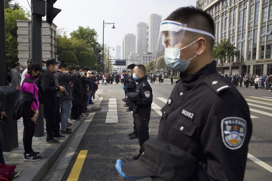 People and policemen bow their heads during a national moment of mourning for victims of coronavirus in Wuhan in central China&#039;s Hubei Province, Saturday, April 4, 2020. With air raid sirens wailing and flags at half-staff, China on Saturday held a three-minute nationwide moment of reflection to honor those who have died in the coronavirus outbreak, especially &quot;martyrs&quot; who fell while fighting what has become a global pandemic.