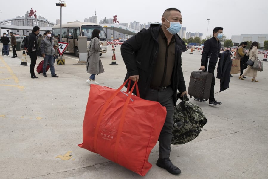 Residents carry their belongings as they walk past a toll booth to enter the city of Wuhan which is still under lockdown due to the coronavirus outbreak but have started allowing some residents to return in central China&#039;s Hubei province on Thursday, April 2, 2020.