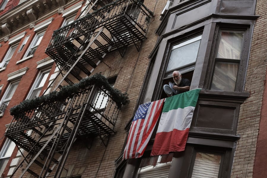 A man leans out the window on Mulberry Street in New York&#039;s Little Italy and bangs together pot lids to show his support for those in the front lines fighting against the coronavirus pandemic, Monday, April 13, 2020. Citywide people open their windows each evening at 7 p.m. to make noise to support the doctors, nurses, hospital staff, EMT&#039;s and front-line workers who are risking their lives every day.