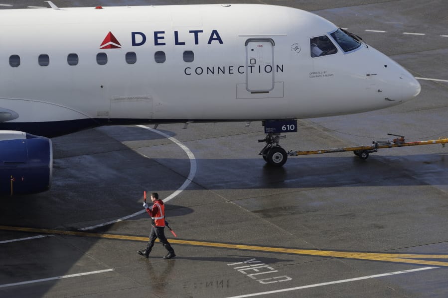 FIE - In this Feb. 5, 2019, file photo a ramp worker guides a Delta Air Lines plane at Seattle-Tacoma International Airport in Seattle. Delta Air Lines says it earned $1.1 billion in the fourth quarter by operating more flights and filling a higher percentage of seats.  The financial results beat Wall Street expectations. Delta and other U.S. airlines are enjoying a prolonged period of profitability thanks to steadily rising demand for travel.   (AP Photo/Ted S.