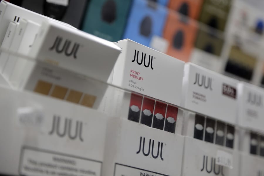 FILE - In this Dec. 20, 2018, file photo Juul products are displayed at a smoke shop in New York.  The Federal Trade Commission on Wednesday, April 1, 2020, sued to break up the multibillion-dollar partnership between tobacco giant Altria and e-cigarette startup Juul Labs.