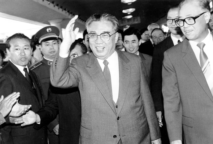 FILE - In this May 21, 1987, file photo, then North Korean President Kim Il Sung, center, and then Chinese Premier Zhao Ziyang make their way through a crowd of well-wishers at the train station in Beijing.
