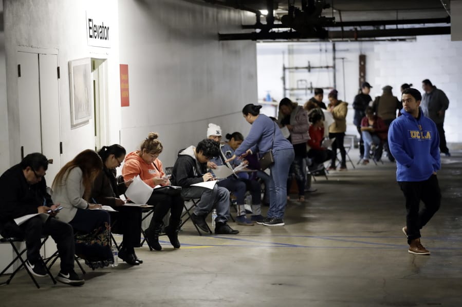 FILE - In this March 13, 2020 file photo, unionized hospitality workers wait in line in a basement garage to apply for unemployment benefits at the Hospitality Training Academy in Los Angeles.  More than 6.6 million Americans applied for unemployment benefits last week, far exceeding a record high set just last week, a sign that layoffs are accelerating in the midst of the coronavirus.