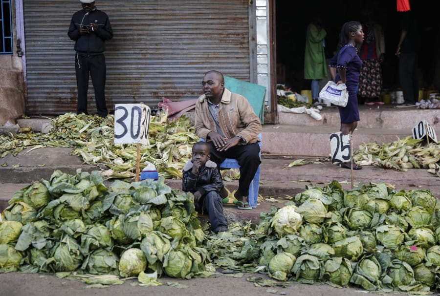 FILE - In this March 24, 2020, file photo, a street trader sells cabbages by the side of the road, after the government ordered the closure of the main open air market, in the Mathare slum, or informal settlement, of Nairobi, Kenya. Lockdowns in Africa limiting the movement of people in an attempt to slow the spread of the coronavirus are threatening to choke off supplies of what the continent needs the most: Food.