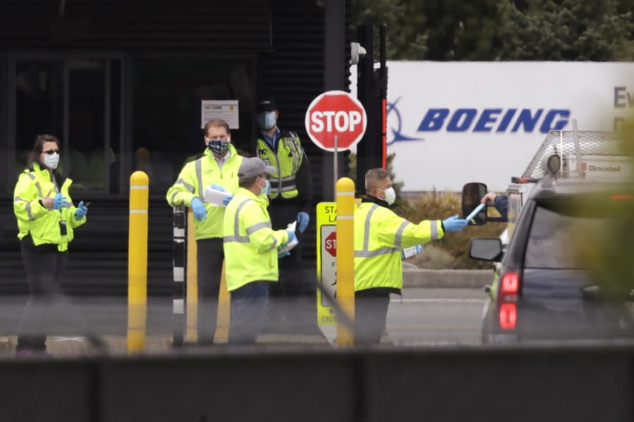 A worker is handed a protective mask while entering a Boeing production plant Tuesday, April 21, 2020, in Everett, Wash. Boeing this week is restarting production of commercial airplanes in the Seattle area, putting about 27,000 people back to work after operations were halted because of the coronavirus.