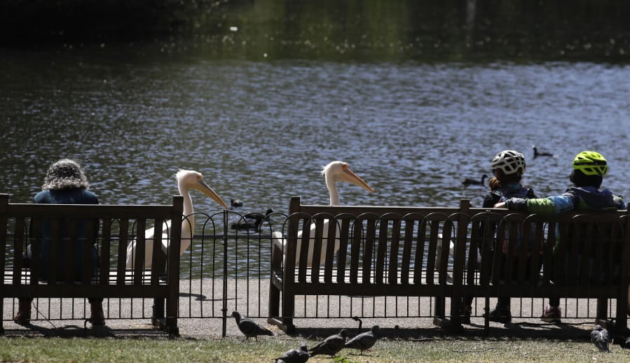 People sit on benches obeying the social distancing in St James&#039;s Park in London, as the country continues in lockdown to help curb the spread of the coronavirus, Sunday, April 19, 2020.