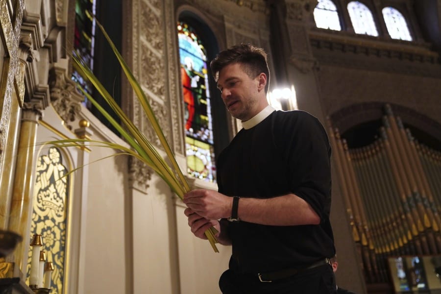 The Rev. Steven Paulikas decorates an altar with palm fronds March 29 for Palm Sunday, which will be commemorated virtually this year, at All Saints&#039; Episcopal Church in the Brooklyn borough of New York.