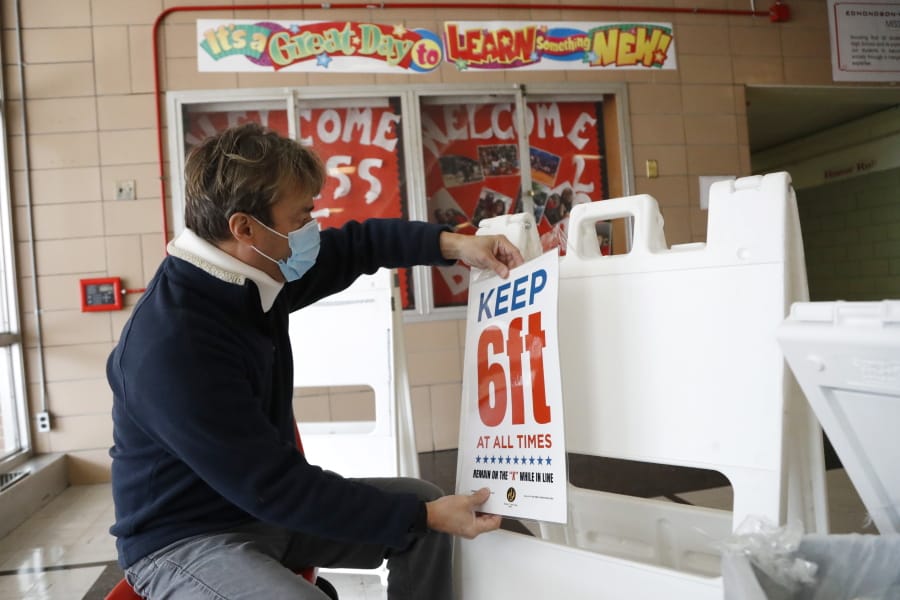 Joshua Ramos, an election technician with the Baltimore City Board of Elections, prepares signs at a polling center ahead of the 7th Congressional District special election at Edmondson High School, Monday, April 27, 2020, in Baltimore. Democrat Kweisi Mfume and Republican Kimberly Klacik won special primaries for the Maryland congressional seat that was held by the late Elijah Cummings. The high school is one of three places where residents will be allowed to vote in person in an effort to contain the spread of the new coronavirus.