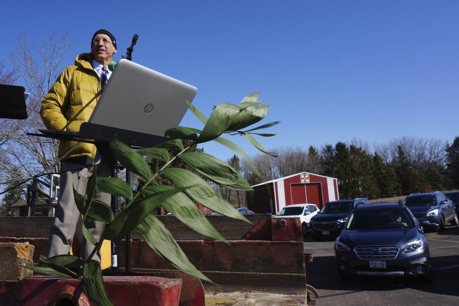 In this April 5, 2020 photo, Pastor John Hanson stands atop a truck as members of his congregation arrive for Sunday morning &quot;drive-in worship&quot; at Peace Lutheran Church in Baldwin, Wis. Palm branches were on display to commemorate Palm Sunday, the beginning of Christianity&#039;s holiest week of the year.