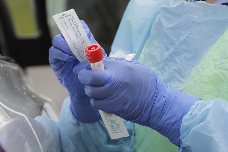A nurse holds a vial and a swab at a drive-up coronavirus testing station at a hospital in Seattle.  (AP Photo/Ted S.