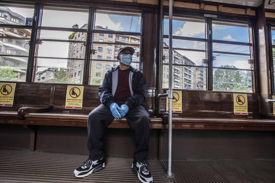 A man sits on a tram as signs reading &#039;please don&#039;t sit here, respect social distancing &#039;, are displayed on the benches, in Milan, Italy, Wednesday, April 29, 2020. Italian factories, construction sites and wholesale supply businesses can resume activity as soon as they put safety measures into place aimed at containing contagion with COVID-19.