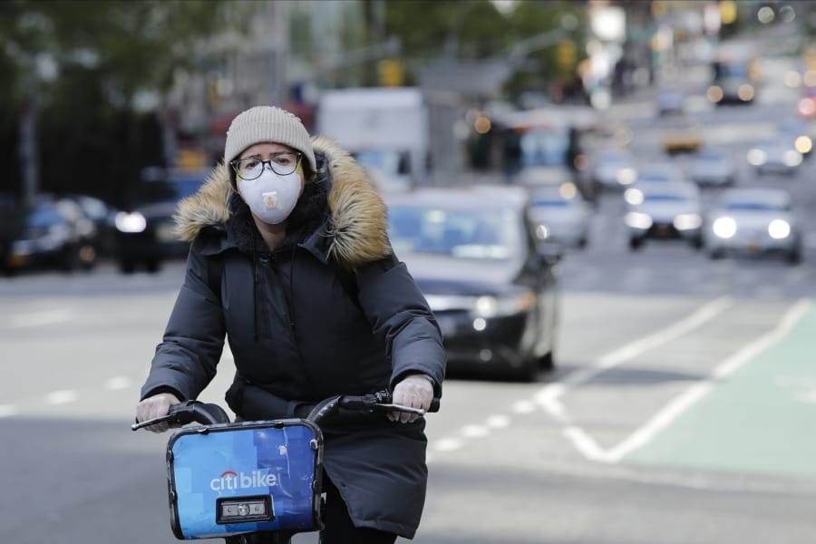 A woman wearing a mask rides a bicycle along second avenue Thursday, April 16, 2020, in New York.