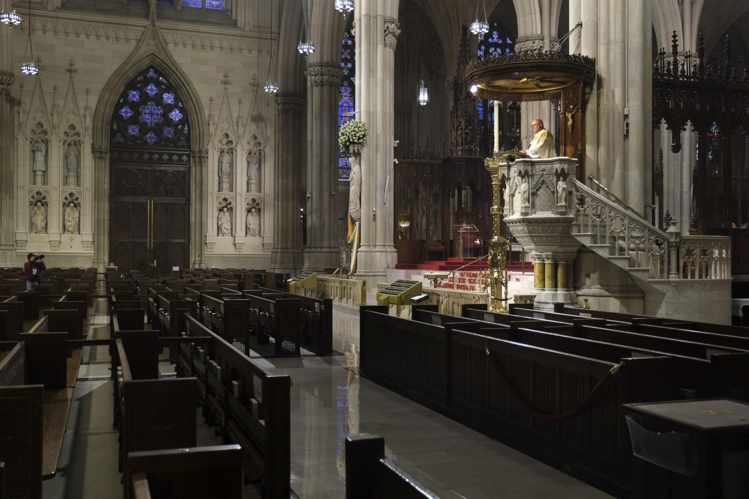 Archbishop Timothy Dolan, right, delivers his homily over empty pews as he leads an Easter Mass at St. Patrick's Cathedral in New York, Sunday, April 12, 2020. Due to coronavirus concerns, no congregants were allowed to attend the Mass but it was broadcast live on a local TV station.