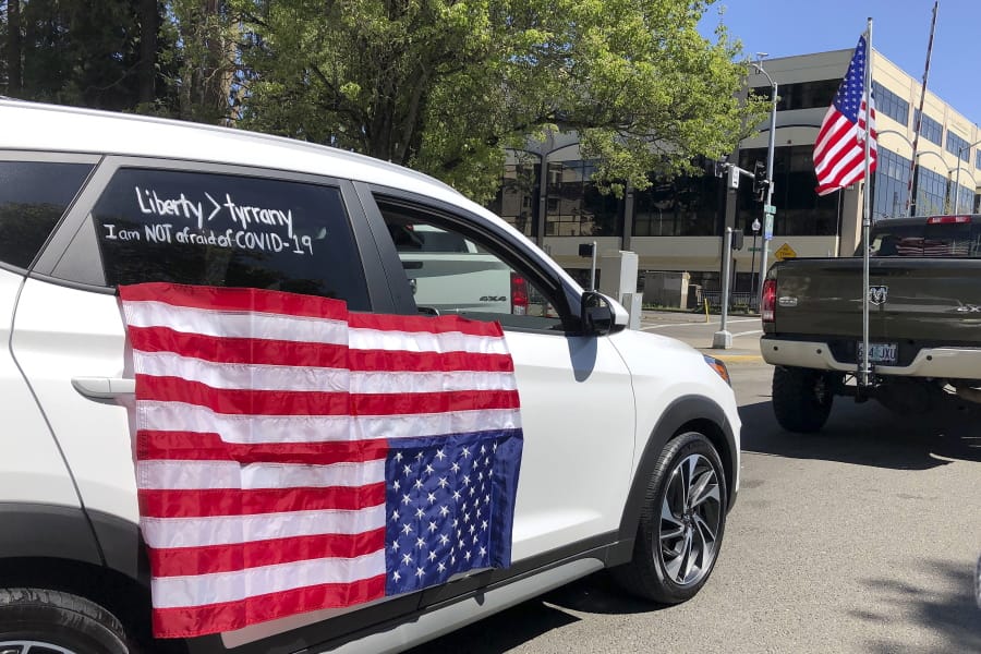 People protesting Oregon Gov. Kate Brown&#039;s stay-at-home order, imposed to prevent the spread of the coronavirus, drive around the State Capitol in Salem, Ore., Friday, April 17, 2020, where they were greeted by other flag-waving protesters.