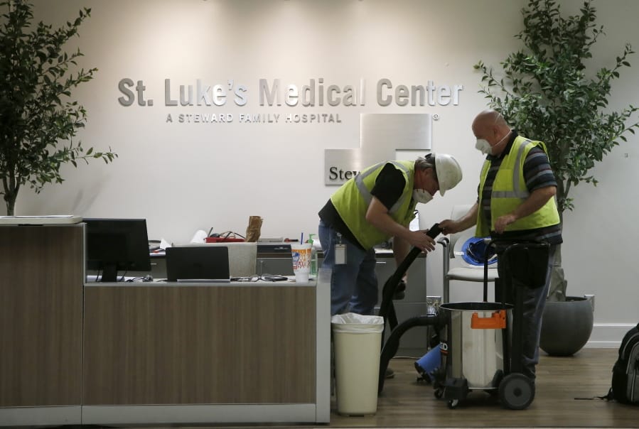 In this April 23, 2020, photo, contract workers join the Army Corps of Engineers as they get the currently dormant St. Luke&#039;s Hospital ready for reopening for the possible surge of coronavirus patients in Phoenix. As states gear up to reopen, a poll finds a potential obstacle to controlling coronavirus: nearly 1 in 10 adults say cost would keep them from seeking help if they thought they were infected. The Gallup-West Health Healthcare Costs Survey out Tuesday, April 28, finds that 9% of those age 18 and over would avoid seeking treatment because of concerns about the cost of care, even if they thought they were infected with the coronavirus.  (AP Photo/Ross D.
