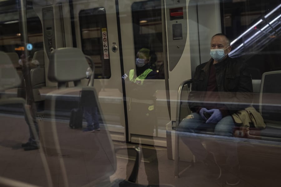 Commuters wearing face masks to protect against coronavirus at Atocha train station in Madrid, Spain, Monday, April 13, 2020. Confronting both a public health emergency and long-term economic injury, Spain is cautiously re-starting some business activity to emerge from the nationwide near-total freeze that helped slow the country&#039;s grim coronavirus outbreak. The new coronavirus causes mild or moderate symptoms for most people, but for some, especially older adults and people with existing health problems, it can cause more severe illness or death.