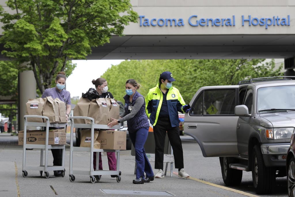 J.D. Elquist, right, of the Downtown Tacoma Partnership, delivers meals to workers at Tacoma General Hospital in Tacoma, Wash., Wednesday, April 29, 2020. The delivery was part of the organization's "Hero Meals" project, which collects donations from the public to purchase meals from restaurants that are then given to healthcare workers, first responders, and other essential workers in the city during the coronavirus outbreak. (AP Photo/Ted S.