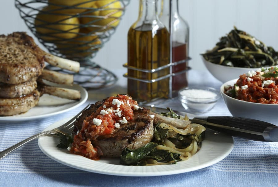 Pork chops are served with a roasted red pepper and feta cheese relish, plus a side of sauteed greens.