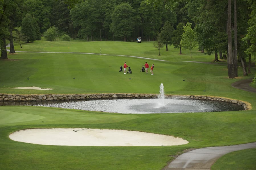 Golfers finish a round at the 18th hole at Camas Meadows golf course.