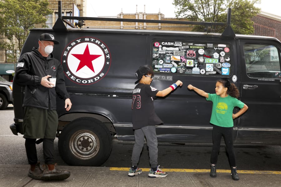 From left: Easy Street Records owner Matt Vaughan is seen with his out-of-school kids Archie, 8; and Daisy, 6, Thursday April 30, 2020 in West Seattle during the coronavirus outbreak. Vaughan, who makes home deliveries of records, credits an extremely loyal customer base and said most of what the store moves are vinyl LPs, which outsell merch and CDs.