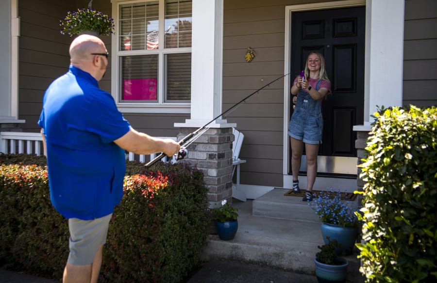 Mountain View High School teacher and coach Dan Larson uses a fishing pole to drop off materials for a fishing license for senior Abby Horton at her home in Vancouver. Larson asked his senior students to all tell him a small thing they wished for that he could help come true. Throughout the last few weeks he&#039;s been completing one of these small acts of kindness for at least one of his students a day.