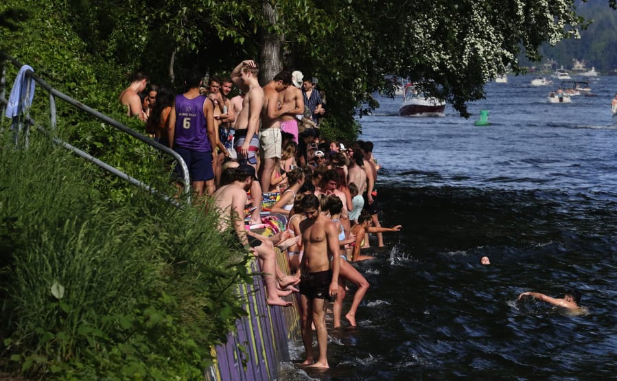 Warm weather, cold water, boats and youth lead to a compact crowd along the north bank of the Montlake Cut east of the bridge.