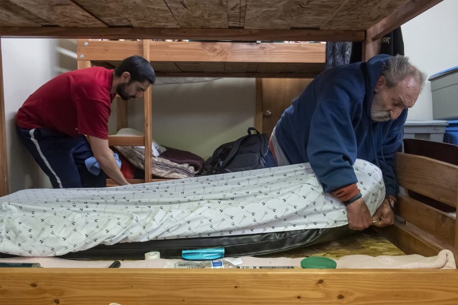 Tyler Taplin, left, and Chad Calhoun make their beds inside the Winter Hospitality Overflow Shelter at St. Paul Lutheran Church in December. Nearly 11,000 safe sleeps occurred at St. Paul or St. Andrew Lutheran Church last winter.