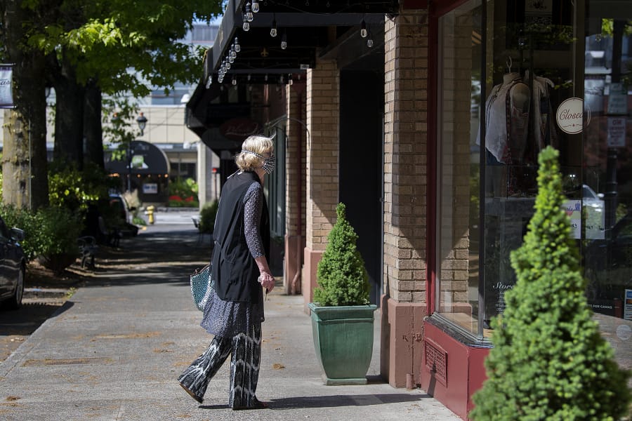 Uta Zuendel, who has lived in Camas since 1974, pauses to check out a window display of a closed boutique as she strolls through a nearly empty Main Street in downtown Camas on May 7.