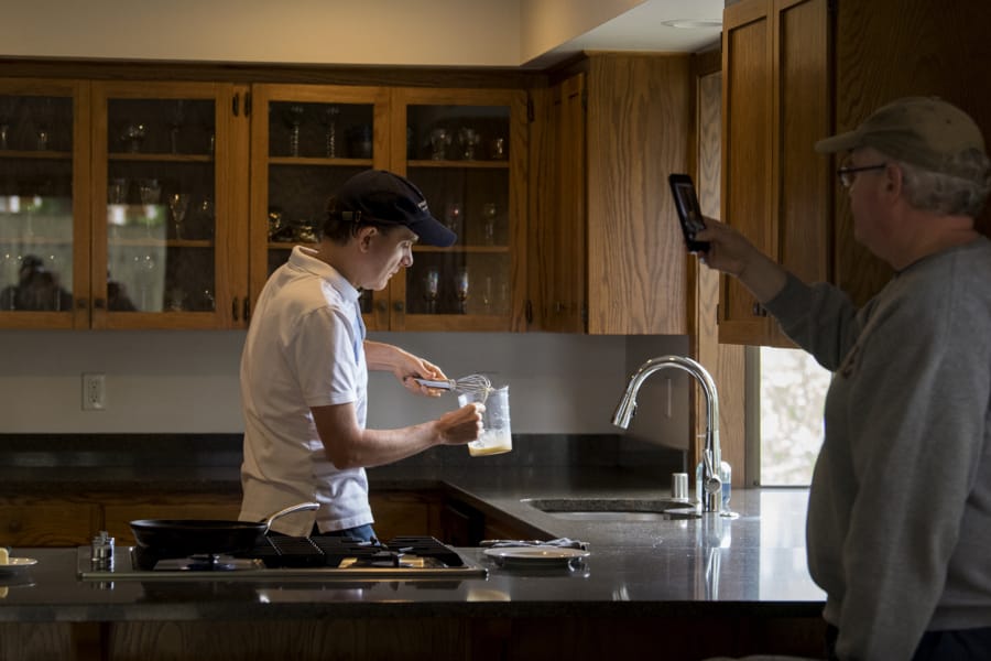Volunteer Kevin Danley, left, whips up some scrambled eggs while making an instructional video with his partner, Kevin McClure, at their Vancouver home. Danley records several instructional cooking videos a week for students at the Washington State School for the Blind.
