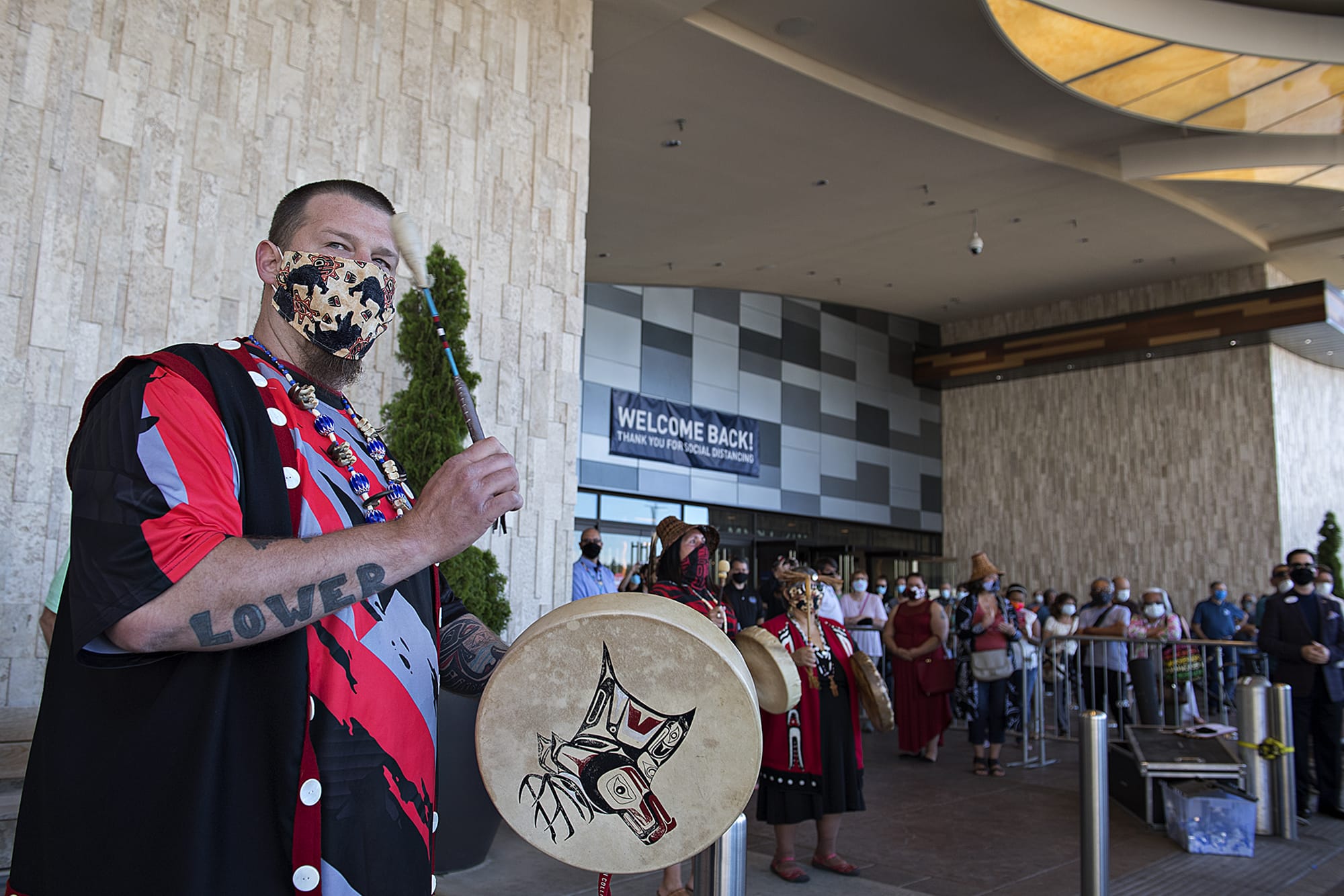 Jeramiah Wallace of the Cowlitz Drum Group, left, keeps the beat while celebrating the reopening of ilani Casino Resort with the crowd on Thursday morning, May 28, 2020.