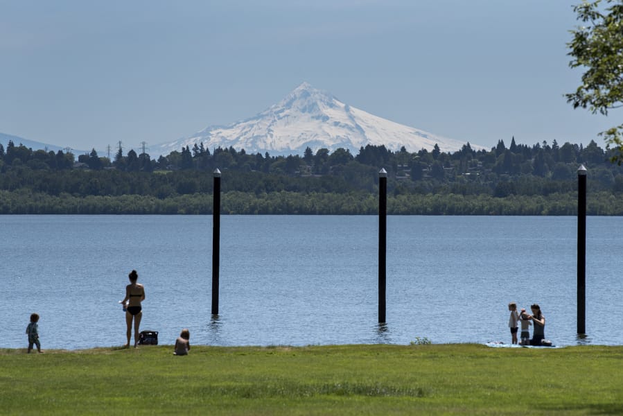 Visitors to Vancouver Lake take in the sunshine and a snow-capped view of Mount Hood while enjoying the day and keeping their distance on Wednesday. The temperature reached 80 degrees Wednesday and will continue to climb today.