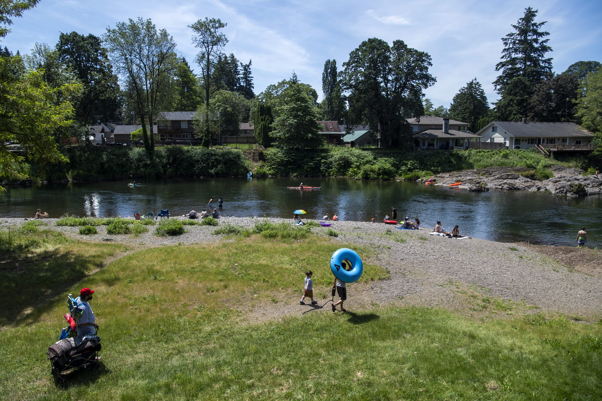 People line the beach on the first day of official reopening at Sandy Swimming Hole Park in Washougal on Friday. The park has been closed due to the COVID-19 public health emergency.