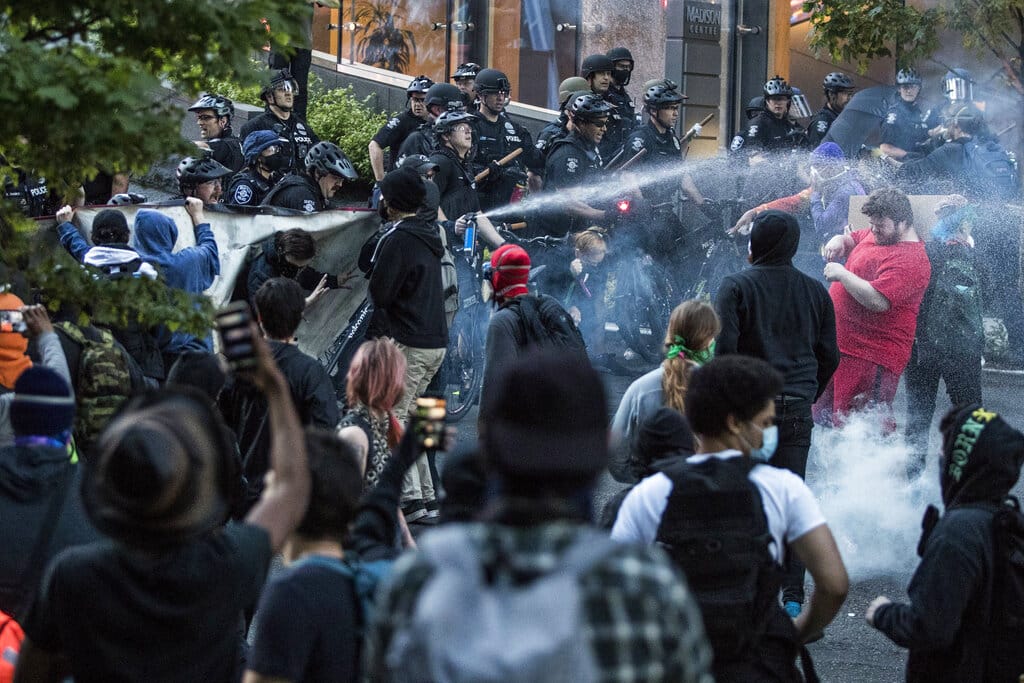 In this May 29, 2020, photo, police push back demonstrators after objects were thrown at them at 5th Avenue and Madison Street during a march in solidarity with Minneapolis and protesting police brutality in Seattle. Protests have been erupting all over the country after George Floyd died earlier this week in police custody in Minneapolis.