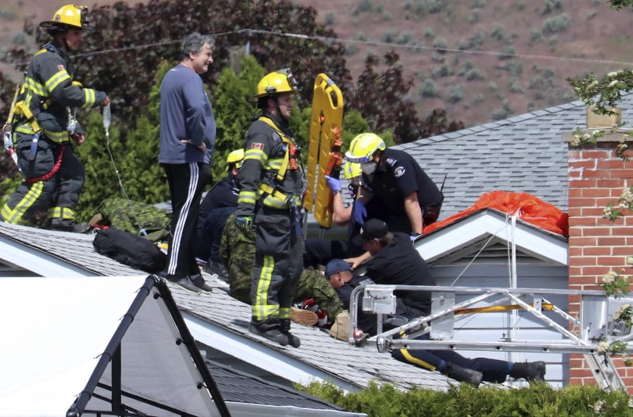 First responders attend to a person on a rooftop at the scene of a crash involving a Canadian Forces Snowbirds airplane in Kamloops, British Columbia, Sunday, May 17, 2020.