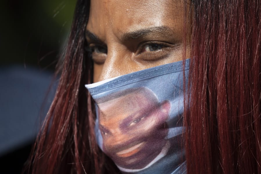 A woman wears a face covering with the likeness of shooting victim Ahmaud Arbery printed on it during a rally to protest Arbery&#039;s killing Friday, May 8, 2020, in Brunswick Ga. Two men have been charged with murder in the February shooting death of Ahmaud Arbery, whom they had pursued in a truck after spotting him running in their neighborhood.