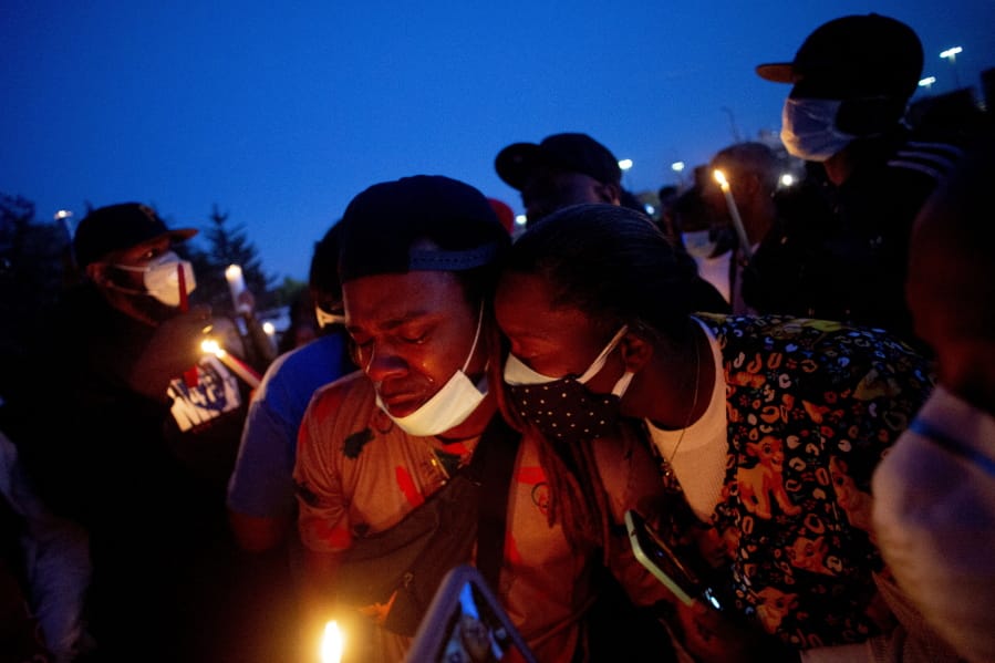 Maalik Mitchell, center left, sheds tears as he says goodbye to his father, Calvin Munerlyn, during a vigil Sunday, May 3, 2020, in Flint, Mich.  Munerlyn was shot and killed Friday at a Family Dollar store in Flint. He&#039;d worked at the store as a security guard for a little more than one year.