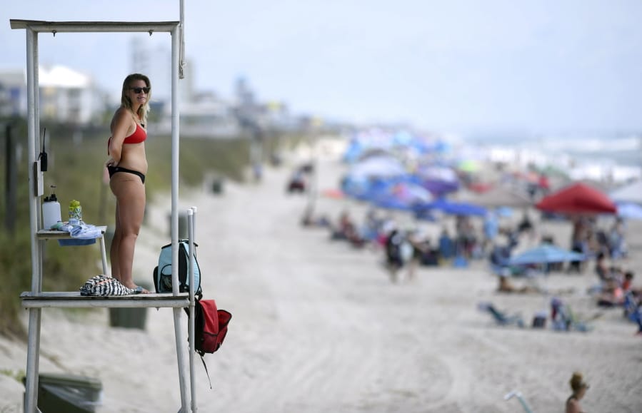 Kure Beach Ocean Rescue lifeguard Katy Kelly looks out from a stand at Kure Beach, N.C., Saturday, May 23, 2020. The town lifted the majority of beach restrictions related to the coronavirus on May 15.